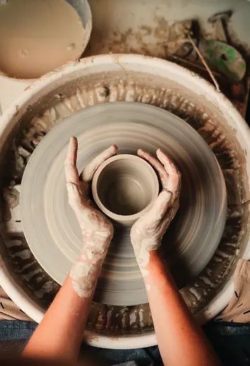 Hands shaping pottery on a wheel